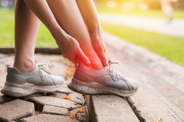 female joggers, pain and discomfort after running in the public park. care and treatment for ankle...