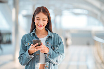 Happy young asian woman using social media on mobile phone on sky walk in a urban city. copy space.