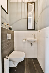 a small bathroom with black and white tiles on the floor, sink, mirror and light fixture in the corner