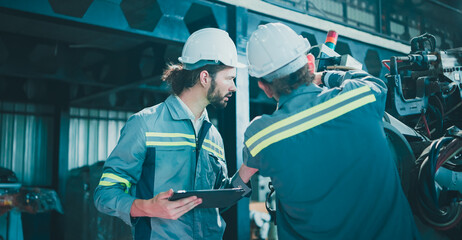 Professional, Team industrial engineer colleague or technician worker wearing safety uniform, hard hat using tablet discuss automated robotic arm machine in factory. Automatic Industry concept.