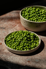 Two plates with fresh sweet pea on stone surface.