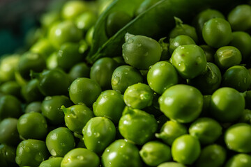 Heap of fresh green peas with open pod on the  top.