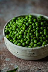 Bowl with fresh sweet peas on stone surface.