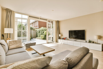 a living room with couches, tv and sliding glass door leading to the patio area in front of the house