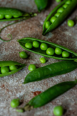 Fresh green peas in pods on stone surface.