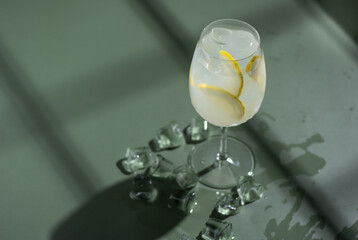 Fresh citrus cocktail with ice on green background with hard light shadows