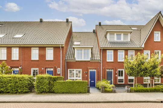 a row of red brick townhouses with white windows and blue sky in the photo is taken on a sunny day