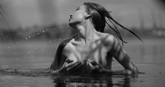 Black and white portrait of woman swimming in a river, slow motion hair toss