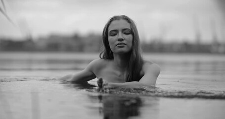 Black and white portrait of woman swimming in a river, slow motion
