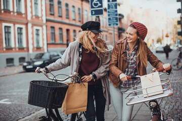 Young women pushing their bicycles on a city street