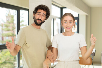 Fototapeta premium young adult couple holding an object with both hands on copy space, showing, offering or advertising an object