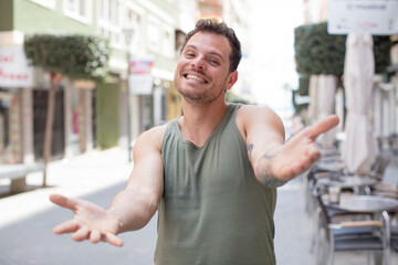 handsome man smiling cheerfully giving a warm, friendly, loving welcome hug, feeling happy and adorable