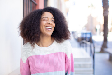 african american pretty woman looking happy and friendly, smiling and winking an eye at you with a...