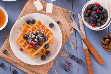 Waffles with red currant and blueberries on white dish. - 624463195