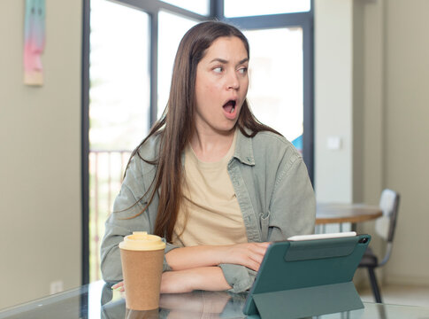 young pretty woman covering mouth with hands with a shocked, surprised expression, keeping a secret or saying oops