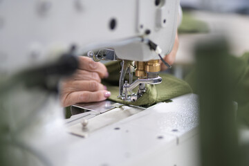 workers in an industrial garment factory sew clothes on sewing machine