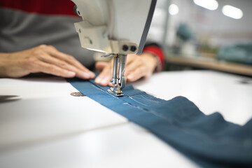 workers in an industrial garment factory sew clothes on sewing machine