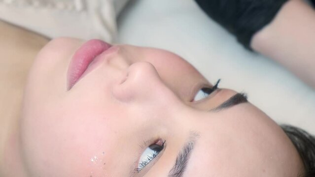 Permanent makeup procedure applying rose red pigment using tattoo machine in beautician salon. Microblading tattoo lips.