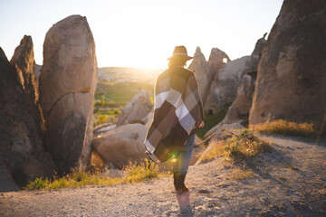 girl hiker in poncho and hat on top of mountain at sunset