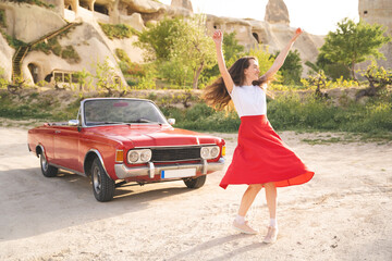 beautiful happy girl in a skirt posing near a retro car in the mountains of cappadocia