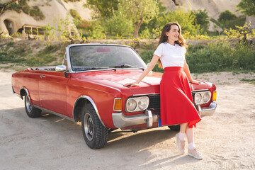 beautiful happy girl in a skirt posing near a retro car in the mountains of cappadocia