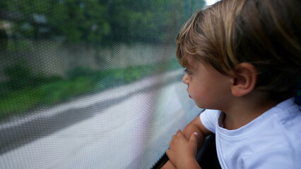 Child staring out bus window traveling by public transportation