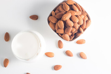 Organic almond milk in glass with raw almonds on white table 