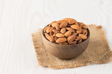 Raw peeled almonds in brown bowl