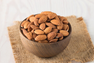 Raw peeled almonds in brown bowl