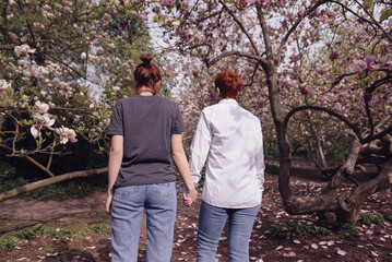 Fototapeta premium Young couple in love walking in cherry blossom sakura in the park