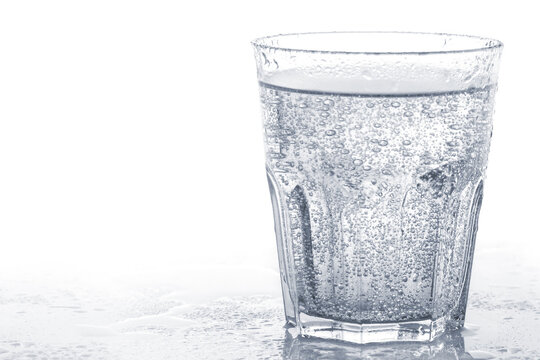 Glass of sparkling soft drink or carbonated water against white background