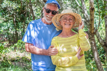 Smiling bonding senior family couple hugging in outdoors enjoying mountain hike in the woods appreciating nature and freedom, retired seniors man and woman and healthy lifestyle concept