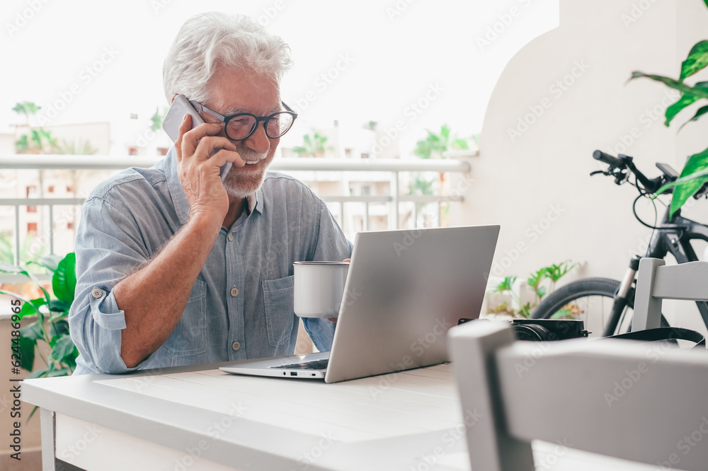 Sticker Happy senior man with eyeglasses talking on mobile phone sitting outdoor on terrace, elderly man using modern technology and wireless connection