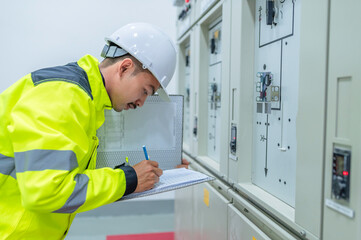 Electrical engineer man checking voltage at the Power Distribution Cabinet in the control room,preventive maintenance Yearly,Thailand Electrician working at company