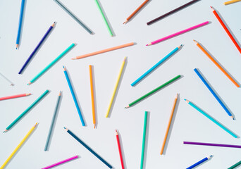 Creative colorful pattern made of colored pencils on white background. Minimal back to school concept. Trendy colored pencils pattern idea. Flat lay background.