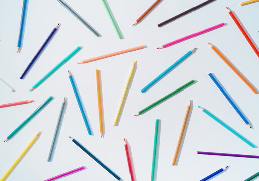 Creative colorful pattern made of colored pencils on white background. Minimal back to school concept. Trendy colored pencils pattern idea. Flat lay background.