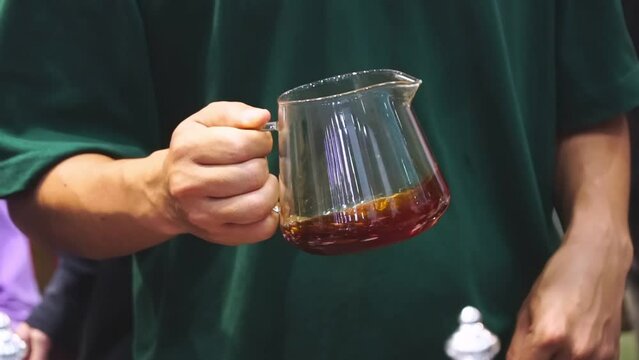 Male hand holding a coffee jug and swaying the coffee to aroma. Male hand holding a jug of freshly brewed hot coffee.