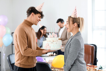 Young man greeting his colleague with Birthday cake at party in office