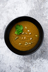 Lentil soup puree with carrots, apples, potatoes, pumpkin seeds and cilantro, vegan food.