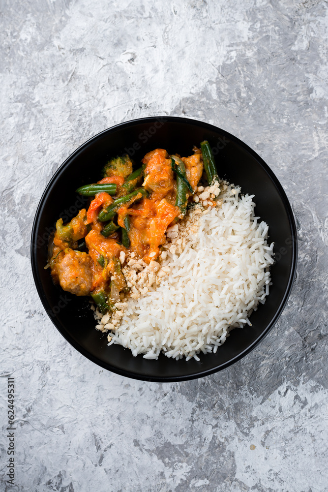 Sticker boiled rice with stew, broccoli, green beans, tomatoes and onions in a bowl, asian food.