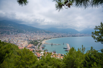 Naklejka premium Aerial view resort city Alanya with harbor and beach in southern coast of Turkey in cloudy day