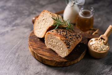 Fresh homemade bread whole wheat baguette white milk and honey on rustic wooden board and abstract table. Sourdough bread
