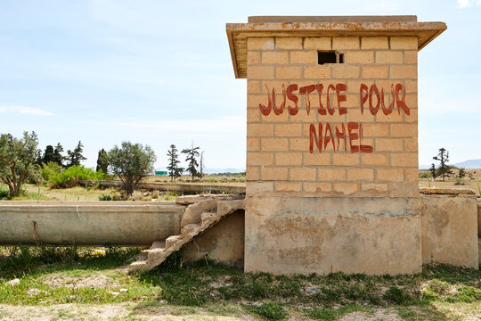 painting french text on brick wall of Water supply channel, Irrigation in countryside of Algeria meaning justice for child named nahel in Nanterre France