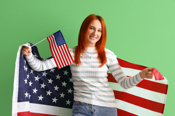 Young redhead woman with USA flags on green background