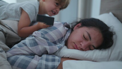 child waking up mother in morning bed jumping on top mom
