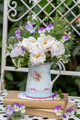 Blumenstrauß mit weißen Rosen und pink Hornveilchen in einem Milchkännchen