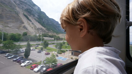 Child inside telepheric transportation going up overlooking landscape kid during vacations