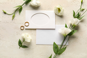 Composition with blank cards, wedding rings and beautiful eustoma flowers on light background