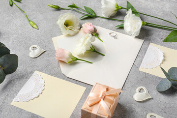Composition with blank cards, engagement ring, envelope and beautiful eustoma flowers on grey background, closeup