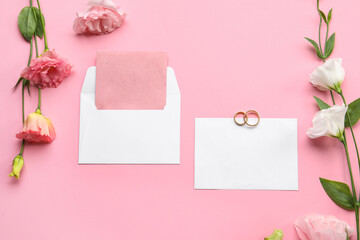 Composition with blank cards, envelope, wedding rings and beautiful eustoma flowers on pink background